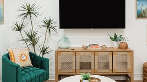 Un saló modern amb un sofà verd, una taula de centre rodona i un gran televisor de pantalla plana fixat a la paret.