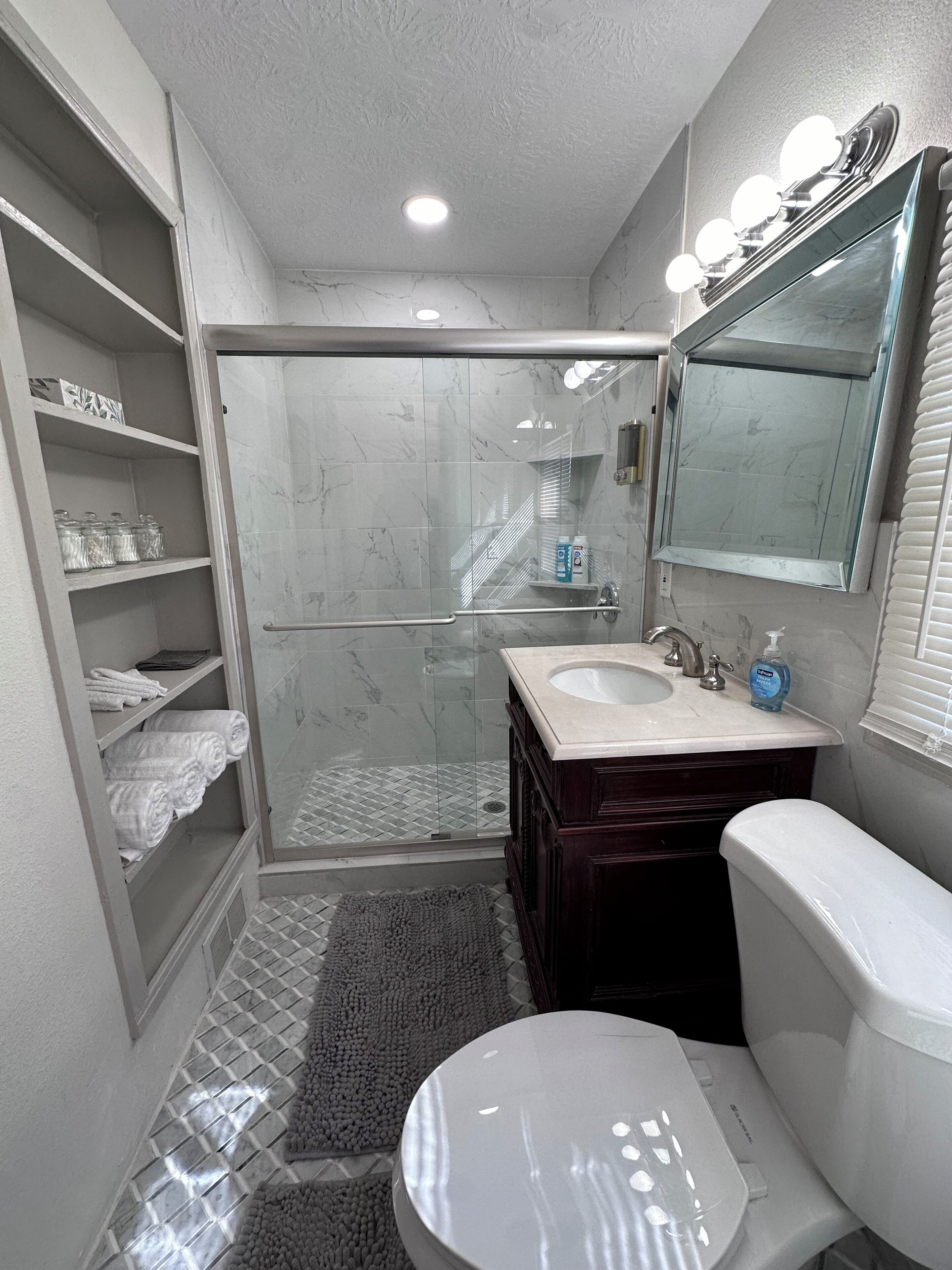 Une salle de bain avec une douche à parois de verre, un meuble-lavabo avec un miroir et des toilettes.