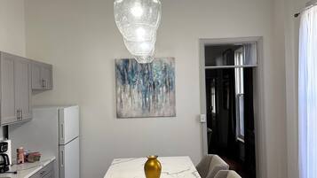 A modern kitchen with a marble island, a pendant light, and a gold vase.