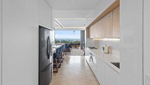 Una cocina moderna con un refrigerador negro, gabinetes blancos y vistas al exterior.