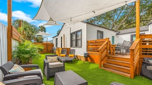 Un espace extérieur aménagé avec des meubles en osier, une terrasse en bois et un bâtiment blanc doté de fenêtres.