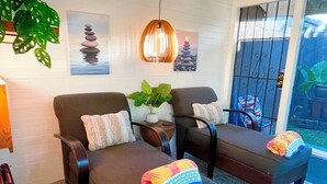 A spa-like room with two dark brown chairs, a hanging light fixture, a potted plant, and artwork on the wall. - Ho’okipa Hideaway - North Shore, Walk to Cafe (Haiku-Pauwela)