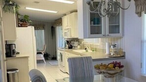 Una cocina moderna con armarios blancos, una mesa de comedor de cristal y una araña.