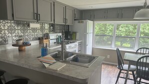Una cocina moderna con una isla grande, electrodomésticos de acero inoxidable y vistas al exterior.