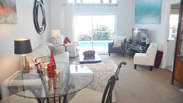 A spacious living room with a glass coffee table, white sofas, a TV, and a view of the ocean. - "NEW to MARKET" <br>Charming 3-Bedroom, 2-Bath Vacation Home in Quiet Gated Community (Davenport)