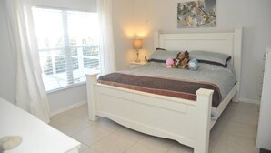A bedroom with a bed, a nightstand, a lamp, a window with curtains, and a painting on the wall. - "NEW to MARKET" <br>Charming 3-Bedroom, 2-Bath Vacation Home in Quiet Gated Community (Davenport)