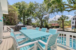 Eine Terrasse im Freien mit einem türkisfarbenen Tisch und Stühlen, einem Grill und einem Pool.