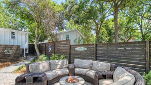 Un patio con mobiliario de mimbre, un hogar y una cerca de madera.