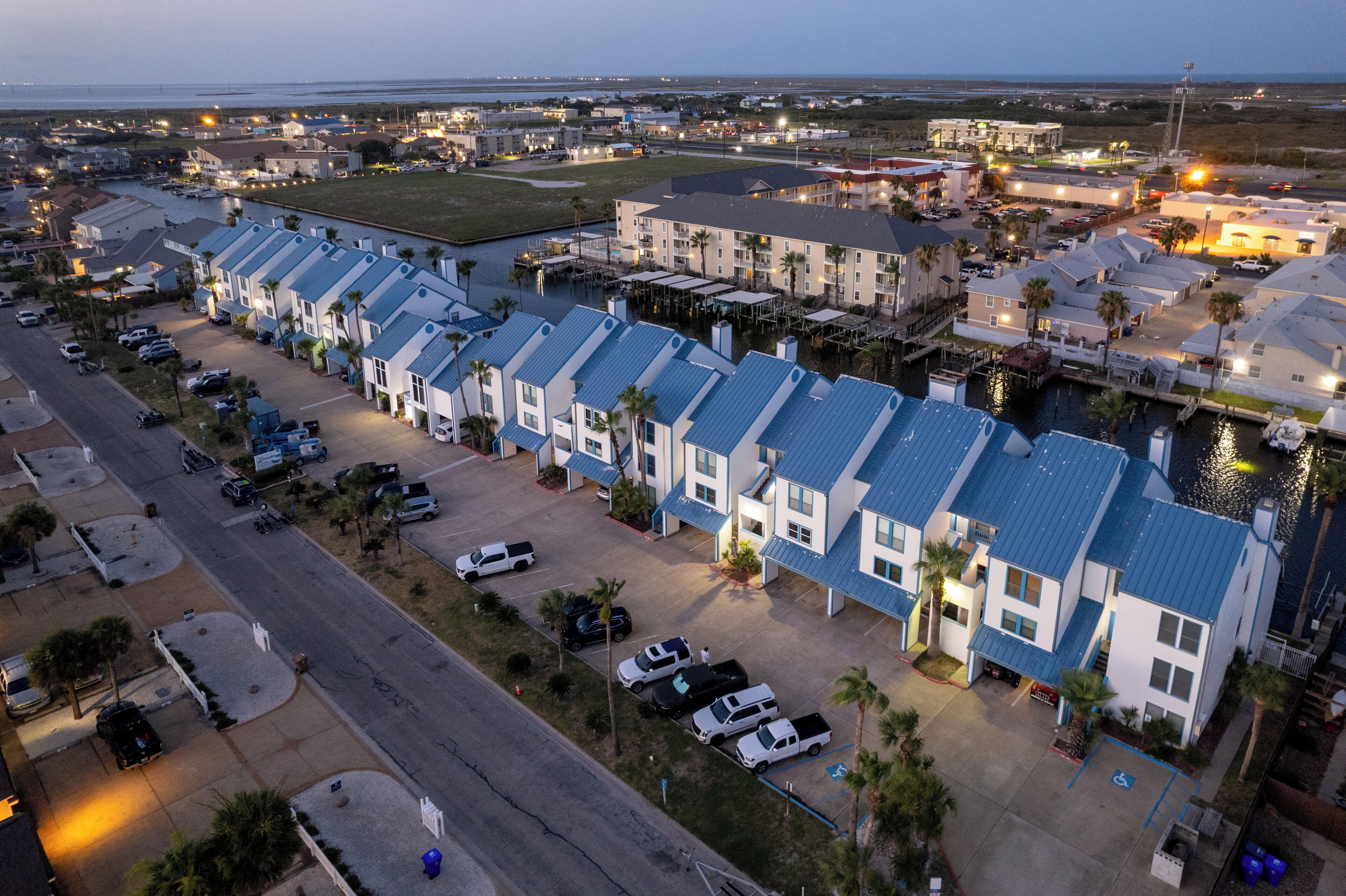 A coastal hotel with a row of rooms, a marina, and a parking lot.