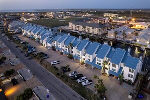 Un hotel frente al mar con una hilera de habitaciones, un puerto deportivo y un estacionamiento.