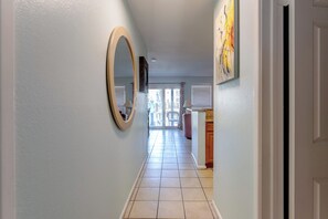 A hallway with a large mirror, a door on the right, and a view into a room with a window and a chair. - 108 1st Floor ! Waterfront !  Pool ! Hot ! Tub   (Corpus Christi)