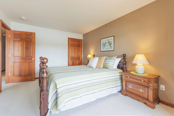 Une chambre à coucher avec un grand lit, une armoire en bois et des lampes de chevet.