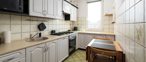A kitchen with white cabinets, a stove, a sink, and a window.