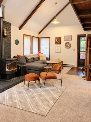 Una sala de estar acogedora con chimenea, un sofá, una mesa de centro y un comedor.