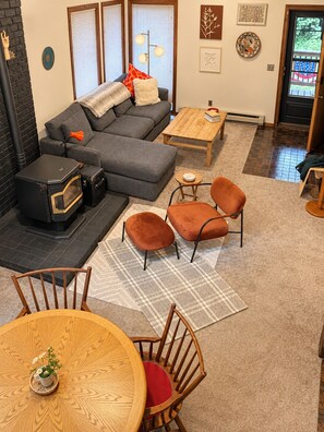 A cozy living room with a sofa, ottomans, a coffee table, and a dining table with chairs.