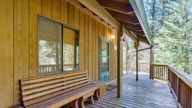 Een houten hut met een veranda, een bank en een deur.