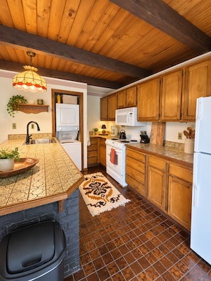 Una cocina con armarios de madera, microondas, estufa y lavaplatos.