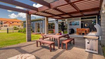 An outdoor patio with a grill, wooden tables, and benches.