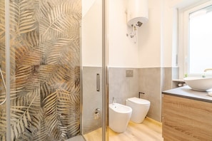 Un bagno moderno con box doccia in vetro, un bidet e un lavabo con una grande vasca.