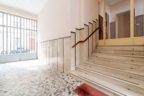 Una scala con ringhiera in legno, pavimento piastrellato e balaustra in vetro.