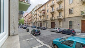 A street view with parked cars, multi-story buildings with balconies, and a clear sky. - Comfortable studio apartment that can comfortably accommodate up to 2 people. The accommodation is located in the quiet Parella district, a very green and well-served area: the MM Pozzo Strada stop is just 350m away and allows you to quickly reach the ce (Torino)