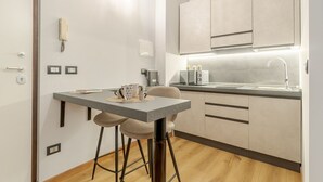 A compact kitchen with a dining area, featuring a table, chairs, a sink, and modern cabinetry. - Comfortable studio apartment that can comfortably accommodate up to 2 people. The accommodation is located in the quiet Parella district, a very green and well-served area: the MM Pozzo Strada stop is just 350m away and allows you to quickly reach the ce (Torino)