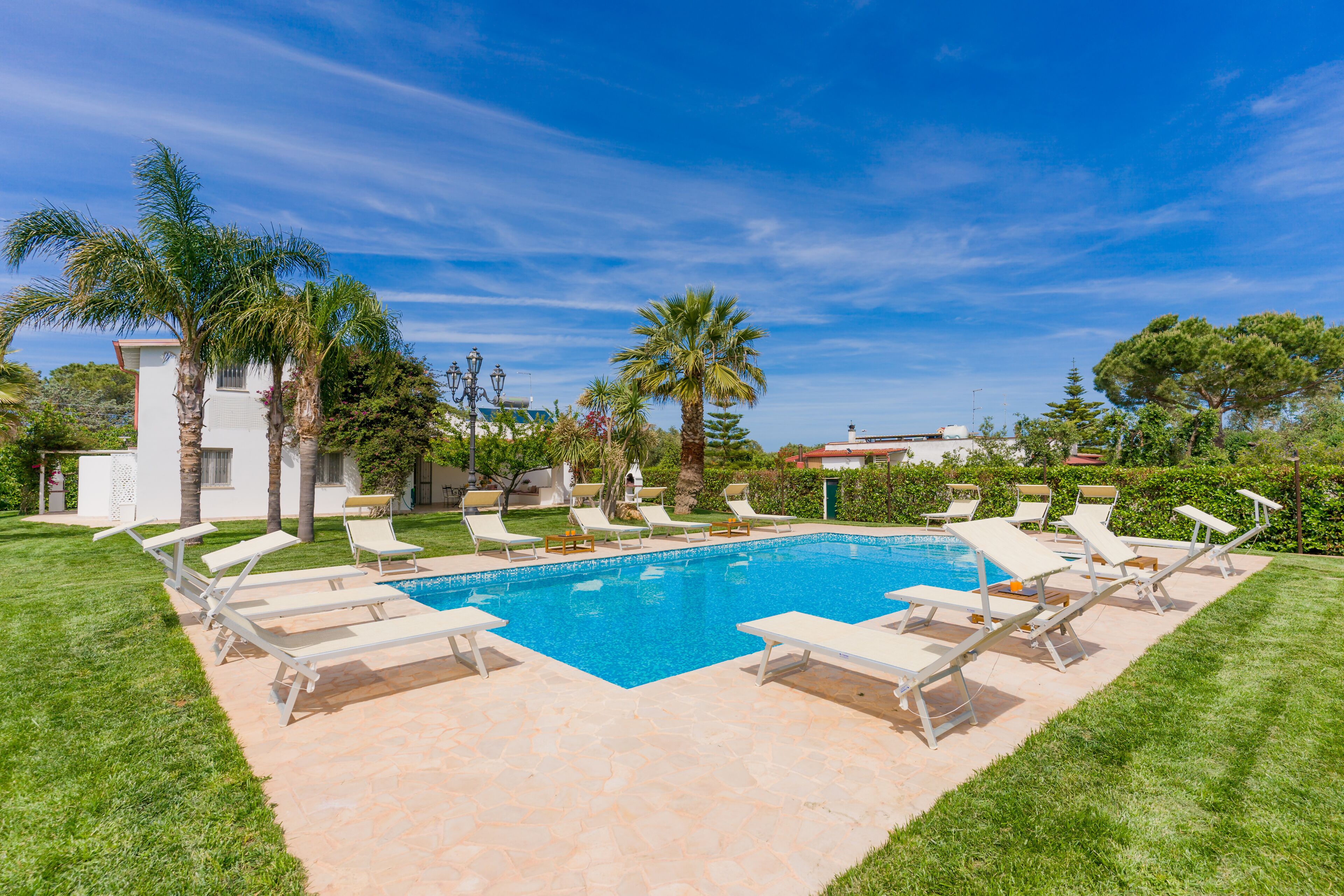 Ein Swimmingpool mit weißen Liegestühlen und Palmen.