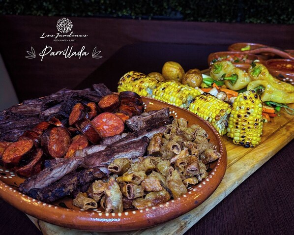 Un assortiment de viandes et de légumes grillés, présentés sur une planche en bois.