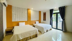 Habitación de hotel con dos camas, un ventanal con cortinas, aire acondicionado de pared y un papel tapiz estampado.