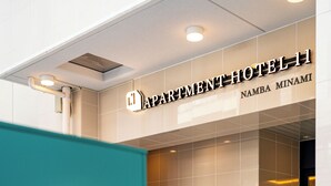 Entrada de un hotel con un letrero que dice 'APARTMENT HOTEL 11' y 'NAMBA MINAMI'.