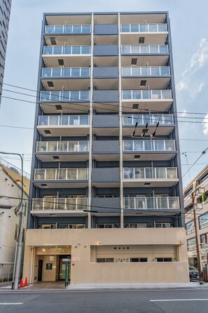 A multi-story hotel with a modern design, featuring balconies on each floor and a ground-level entrance. - Apartment Hotel 11 Namba Minami (Osaka)