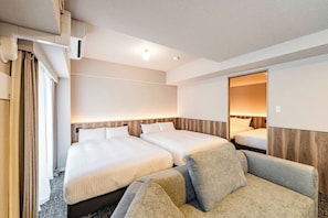 Une chambre d’hôtel avec deux lits, un canapé et un miroir.