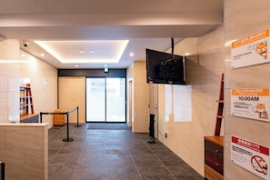 A hotel lobby with a reception desk, a television mounted on the wall, and a sign indicating check-out time. - Apartment Hotel 11 Namba Minami (Osaka)