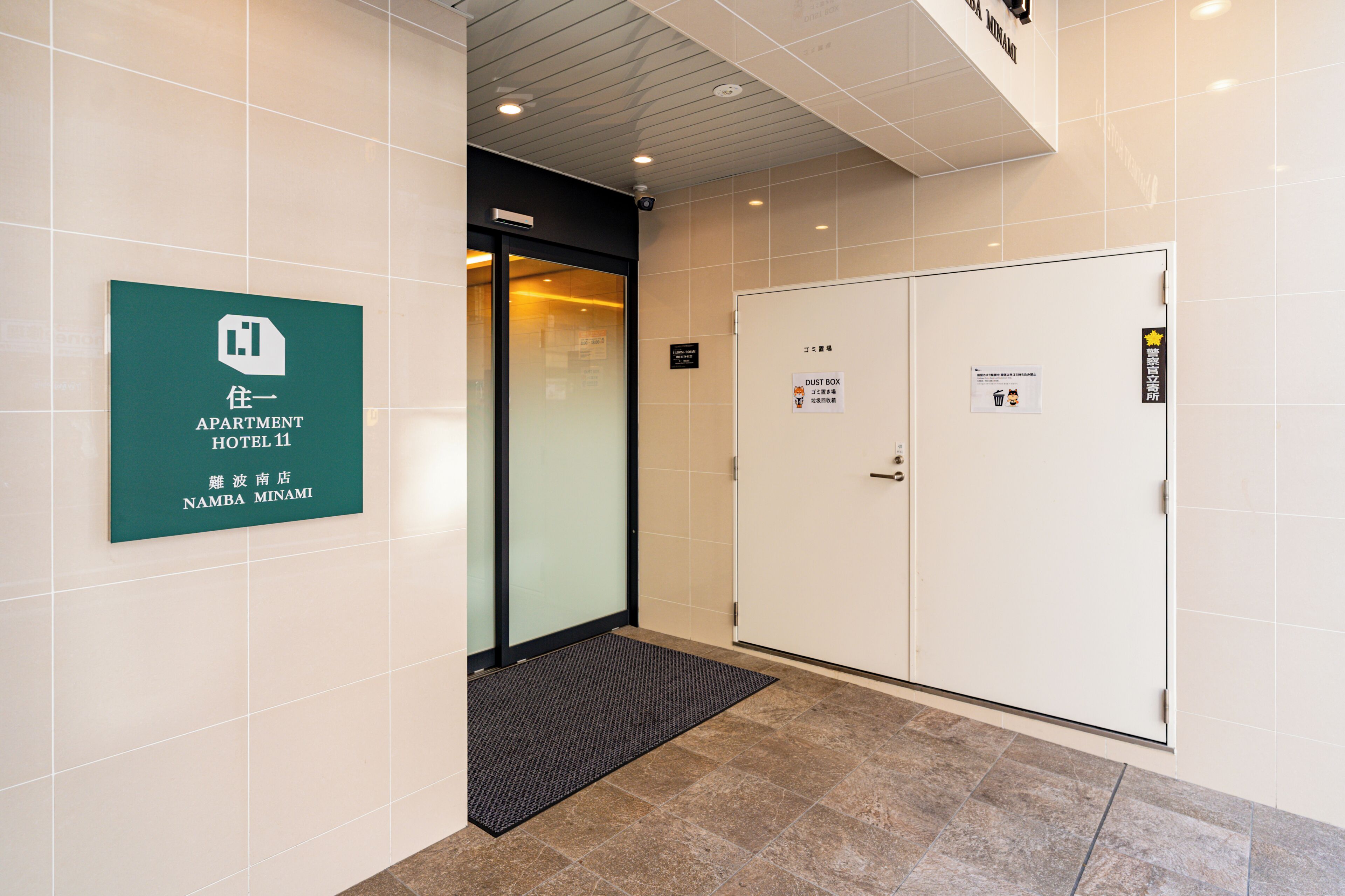 Ein Hotel Eingang mit einem Schild für 'Apartment Hotel 11' und einem Schild mit der Aufschrift 'STABBOX'.