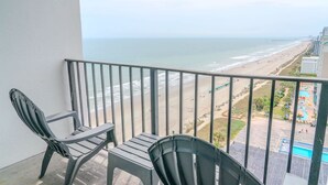 Ein Balkon mit zwei Stühlen, Blick auf den Strand und einen Poolbereich.