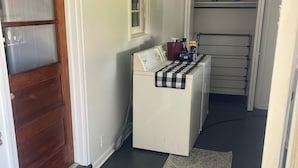Ein Waschbereich mit Waschmaschine, Wäscheständer und einem kleinen Fenster.
