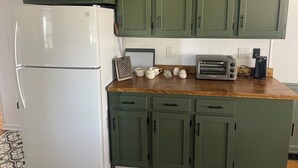 Eine Küche mit grünen Schränken, einem weißen Kühlschrank, einem Toaster und einer Kaffeemaschine auf der Arbeitsfläche.