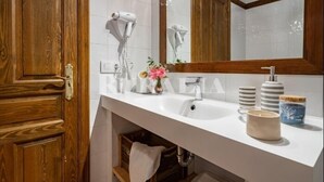 A bathroom with a wooden door, white sink, and a mirror with a wooden frame. - Entrenueces 2 - rural apartment in Camango (Ribadesella) | 4 guests (Camango)