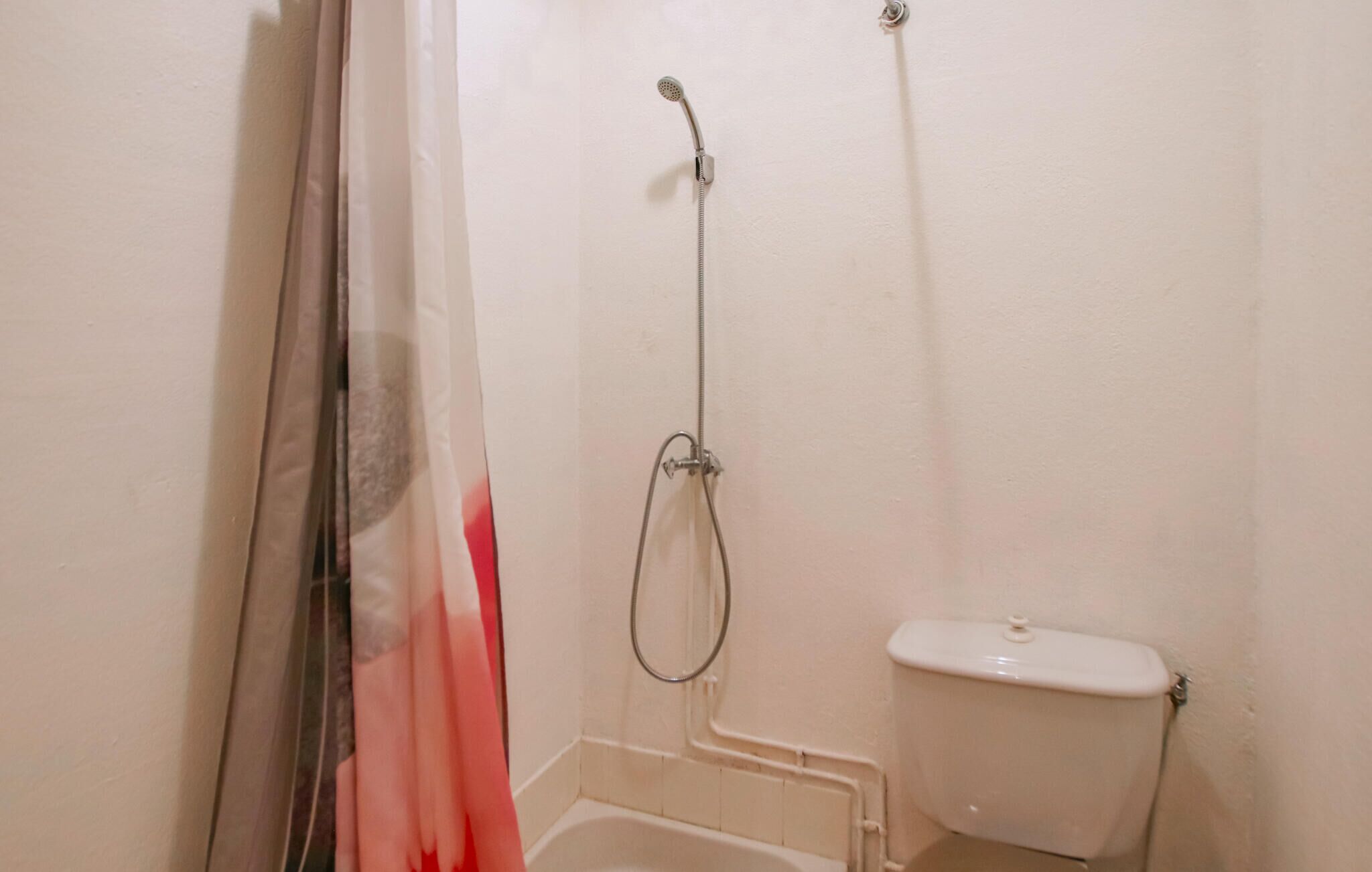 Et badeværelse med bruser, toilet og badeforhæng.