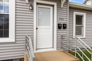A residential house with a front door, a mailbox, and a number '201' on the wall.