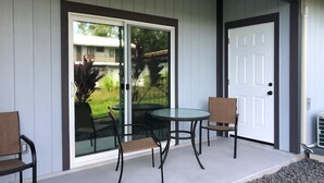Une terrasse avec une porte vitrée, deux chaises et une petite table.