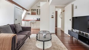 En moderne stue med sofa, sofabord i glas og et fladskærms-tv.