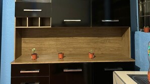 A compact kitchen with dark cabinetry, a wooden countertop, and three small potted plants. - La Casa De Detours Costa Rica (La Fortuna)