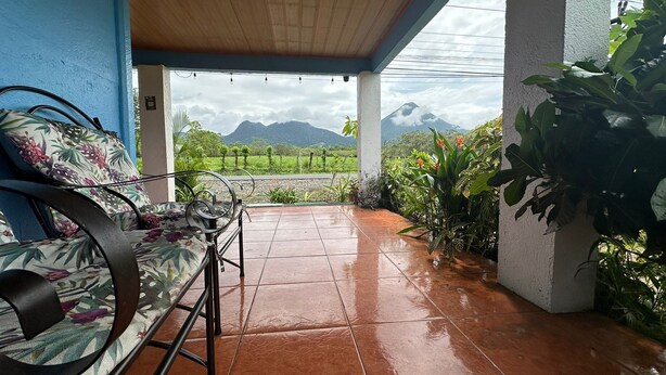 A covered patio with a bench and potted plants, overlooking a mountainous landscape. - La Casa De Detours Costa Rica (La Fortuna)