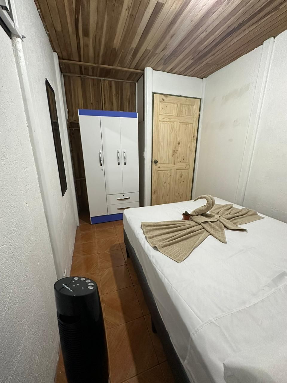 Una habitación pequeña y limpia, con una cama, un armario y una puerta.