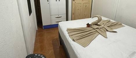 Una habitación pequeña y limpia, con una cama, un armario y una puerta.