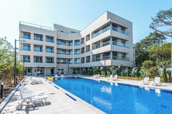 Edifici modern amb piscina, diversos balcons i espai exterior per seure.