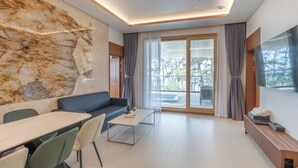 A modern living room with a marble wall, a sofa, a dining table, and a TV. - DONGHO BEACH HOTEL (Gochang)