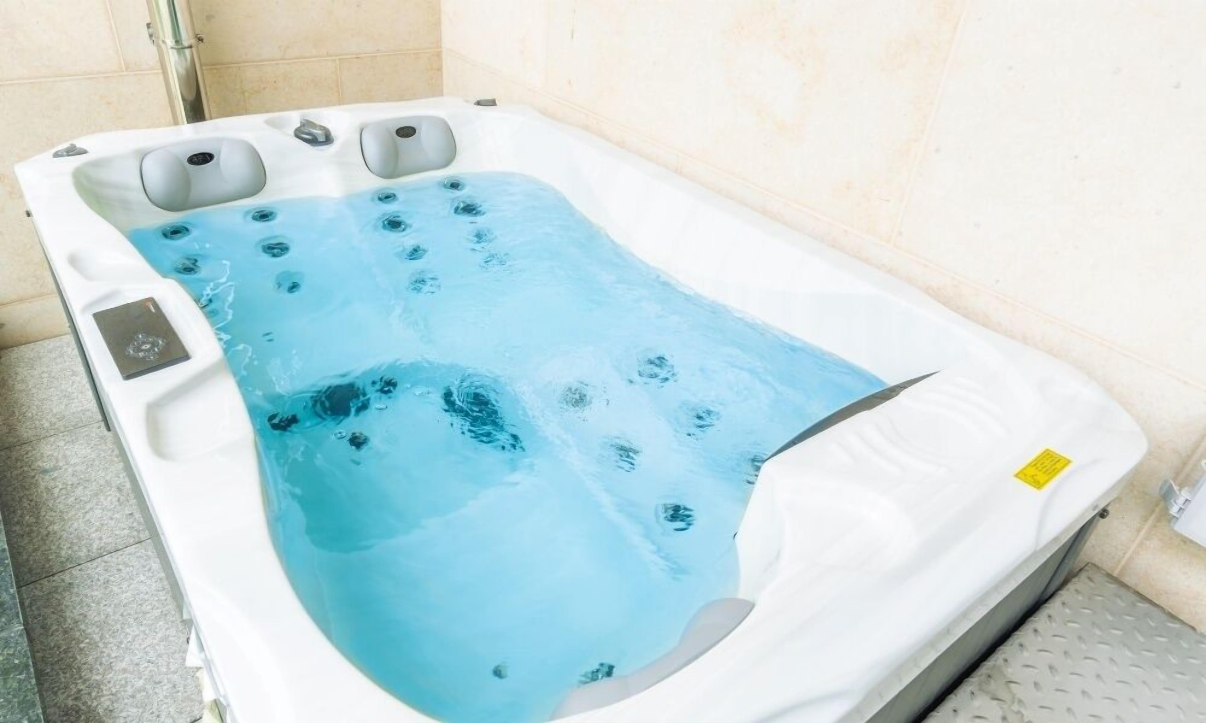 Un jacuzzi con superficie de agua azul cristalina, múltiples chorros y un panel de control.