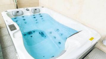 Un jacuzzi con superficie de agua azul cristalina, múltiples chorros y un panel de control.
